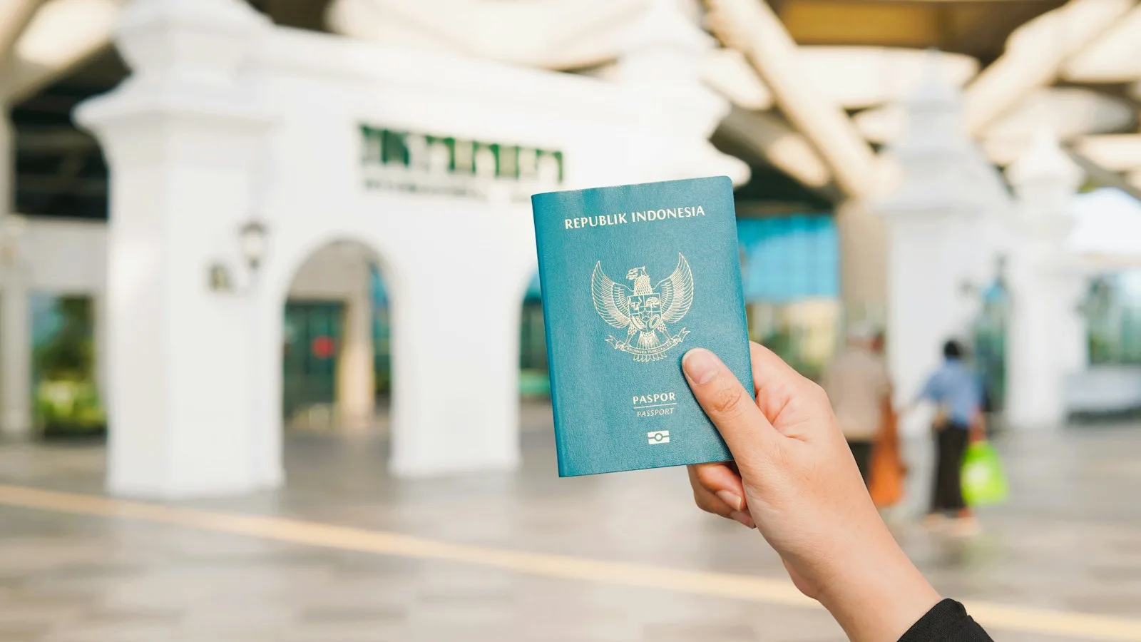 Passeport tenu à la main dans un terminal d'aéroport avant un départ pour l'Indonésie